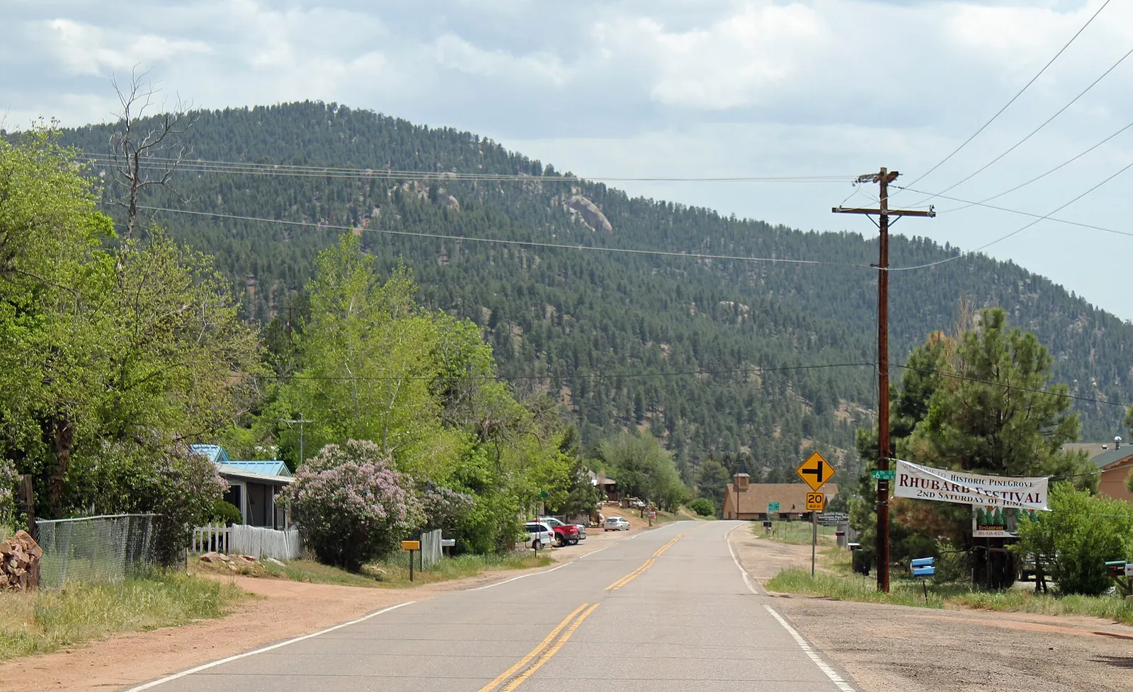 Main street in Pine, Colorado with forested mountains rising behind the town