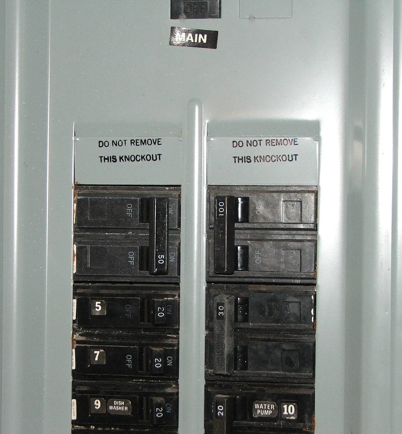 Electrician examining breakers inside an open electrical panel